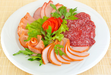 Dish with pastrami and salami slices decorated beautifully.