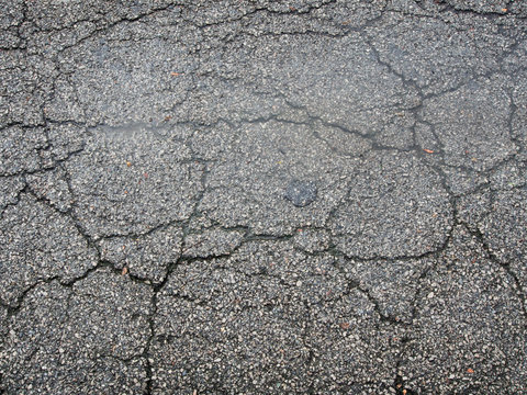 Old wet worn and cracked asphalt with cracks