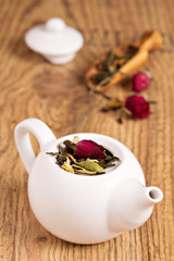 Green tea with fruits, spices, rose petals in white teapot