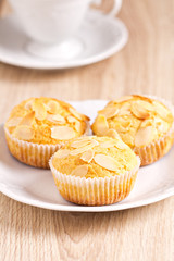 Three muffins with almonds on a plate