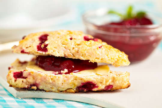 Scone with orange zest and berries with butter and jam