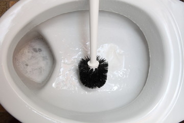 cleaning a toilet bowl with brush