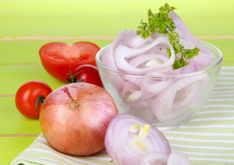 Onion cut with rings in bowl on wooden table close-up