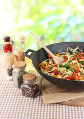 Noodles with vegetables on wok on nature background