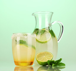Lemonade in pitcher and glass on turquoise background