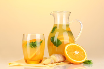 Orange lemonade in pitcher and glass on yellow background