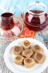 Sweet baklava on plate with tea on table