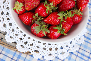 Strawberries in plate on wicker stand on napkin close-up