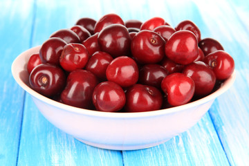 Cherry berries in bowl on wooden table close-up
