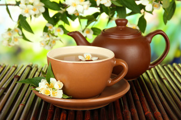 Cup of tea with jasmine, on bamboo mat, on bright background