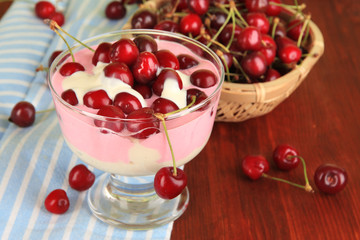 Delicious cherry dessert in glass vase on wooden table close-up