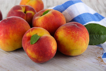 Peaches on board on napkin on table on wooden background