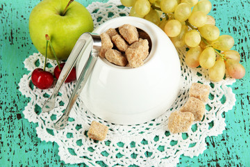 Unrefined sugar in white sugar bowl on wooden background