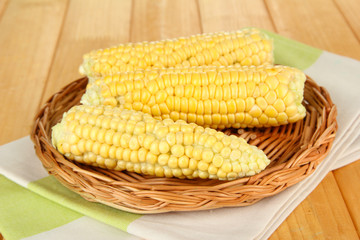 Fresh corn on wicker mat, on wooden background