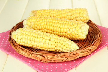Fresh corn on wicker mat, on wooden background