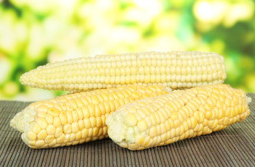 Fresh corn on bamboo mat, on bright background