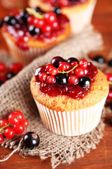 Tasty muffins with berries on wooden table