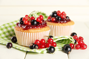 Tasty muffins with berries on white wooden table