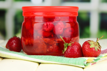 Home made berry jam on wooden table on window background