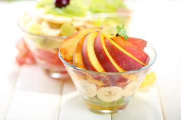Tasty fruit salad in glass bowls, on white wooden table