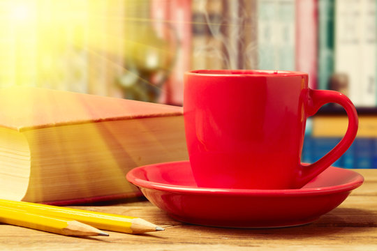 Red coffee cup with books and pencils
