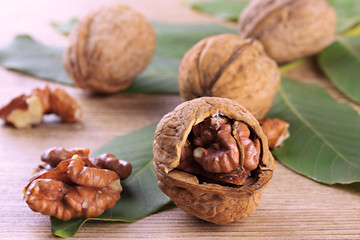 walnuts with green leaves, on wooden background