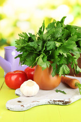 Fresh herb in pitcher on wooden table on natural background