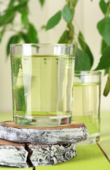 Glasses of birch sap on green wooden table