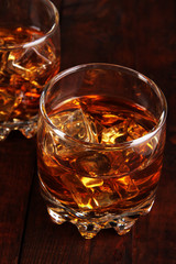 Brandy glasses with ice on wooden background