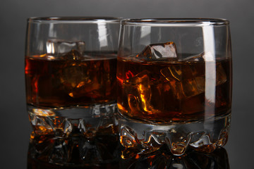Brandy glasses with ice on grey background