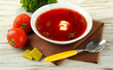 Bowl of soup with bouillon cubes on wooden table