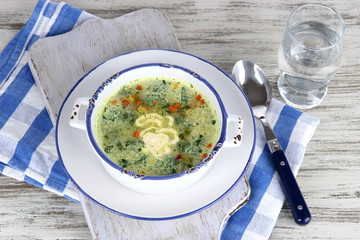 Soup in plate on napkin on wooden board on table