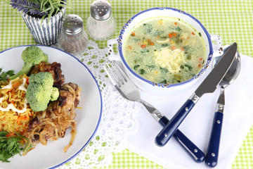 Soup and rice with meat in plates on napkin on tablecloth