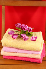 Towels and flowers on wooden chair on red background