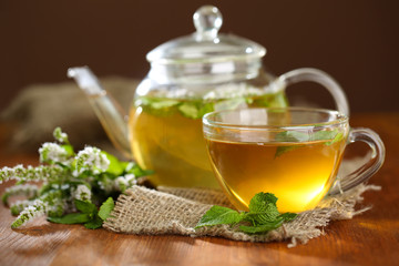 Cup and teapot of herbal tea with fresh mint flowers