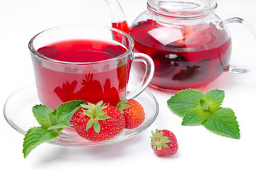 kettle and cup of red tea with strawberries and mint on a white