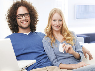 Young smiling couple using credit card and shopping on internet