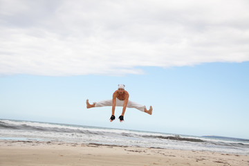 Fototapeta na wymiar erwachsener sportlicher mann am strand springt karate