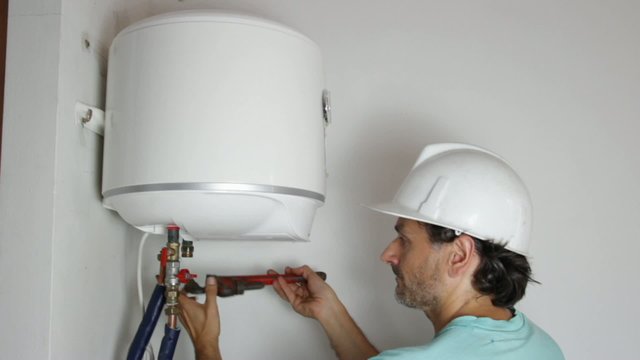 plumber with pipe wrench connecting pipes