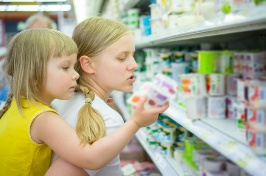 Mother with daughter on back select products in supermarket