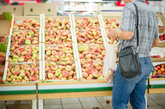 Customer select flat peaches in supermarket