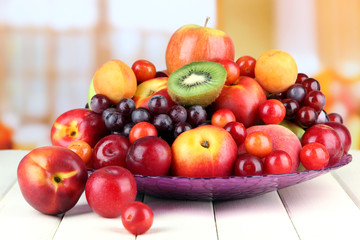 Assortment of juicy fruits on wooden table, on bright
