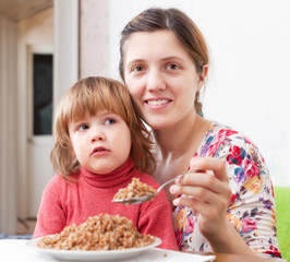 Woman with child eats buckwheat
