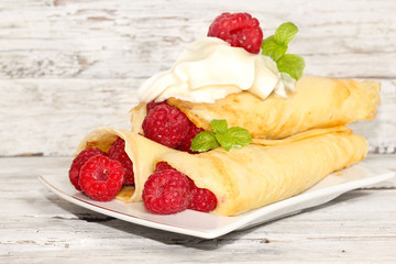 Delicious pancakes with raspberries on the wooden table