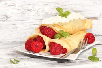 Delicious pancakes with raspberries on the wooden table