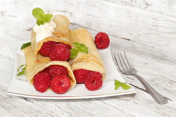 Delicious pancakes with raspberries on the wooden table