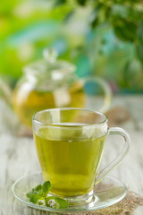 Cup of herbal tea with fresh mint flowers on wooden table