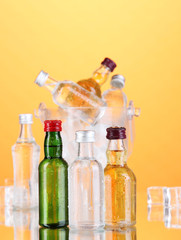 Minibar bottles in bucket with ice cubes,  on color background