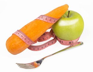 Measuring tape wrapped around a green apple and carrot
