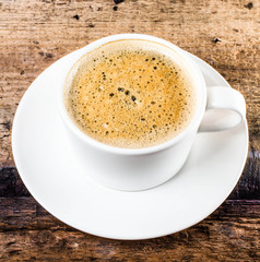 Closeup cup of espresso on old wooden table over grunge backgrou
